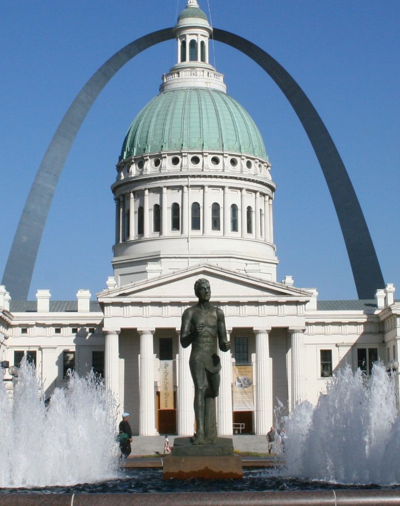 Runner Statue in front of old courthouse and arch